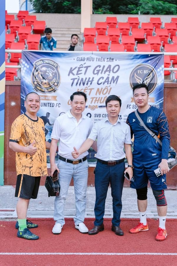 Thành viên hai đội trước băng rôn giao hữu với FC 85+